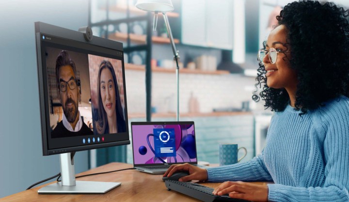 Eine Frau benutzt einen Laptop, der an einen Dell 24-Videokonferenzmonitor angeschlossen ist.