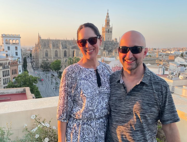 Meine Frau Julie und ich haben letzten Monat während unseres Aufenthalts in Sevilla, Spanien, an einem Paella-Kochkurs auf dem Dach teilgenommen.  Im Hintergrund ist die Catedral de Sevilla zu sehen.  Dieses Foto wurde mit Julies iPhone 12 aufgenommen, nachdem ich meines verloren hatte.