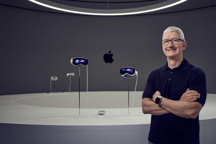 Apple-Chef Tim Cook steht vor vier Vision Pro-Headsets.