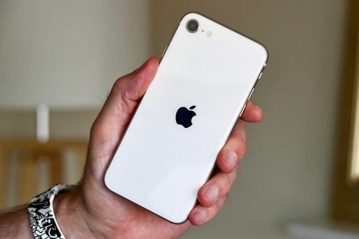 Das Apple iPhone SE (2022) wird in der Hand eines Mannes gehalten.