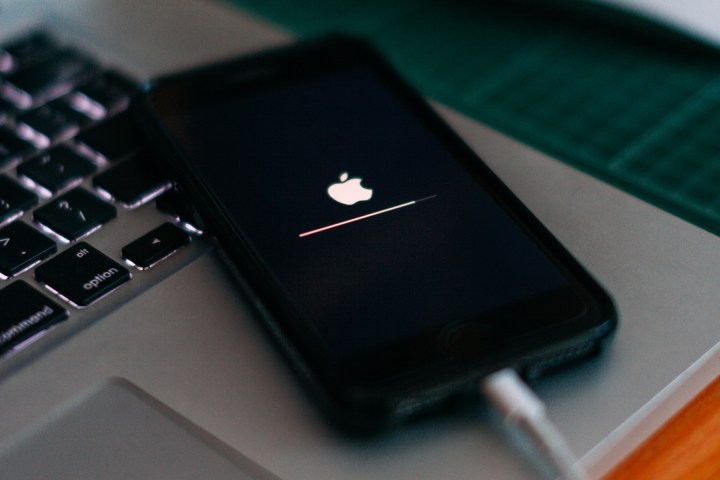 Ein an ein MacBook angeschlossenes iPhone zeigt während einer Software-Update-Wiederherstellung das Apple-Logo.
