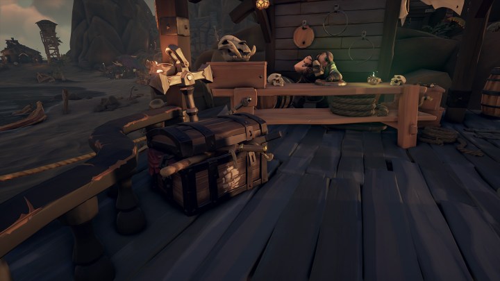 Eine Seetruhe steht auf einem Dock vor dem Schiffsbauertisch in Sea of ​​Thieves