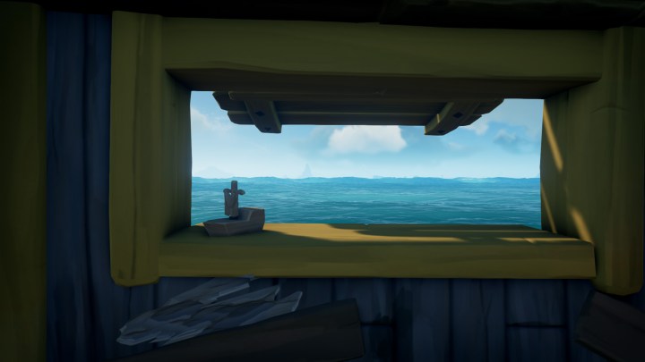Ein kleines Fenster auf einer Schaluppe mit Blick auf das Meer, auf dem eine hölzerne Bootsdekoration angebracht ist.
