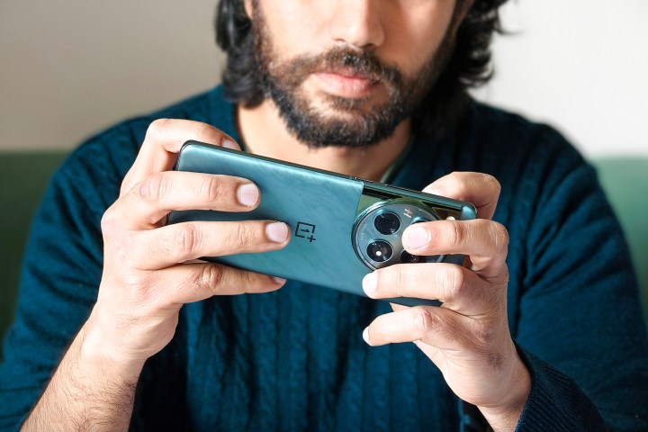 Person, die beim Spielen ein grünes OnePlus 12-Telefon in der Hand hält.