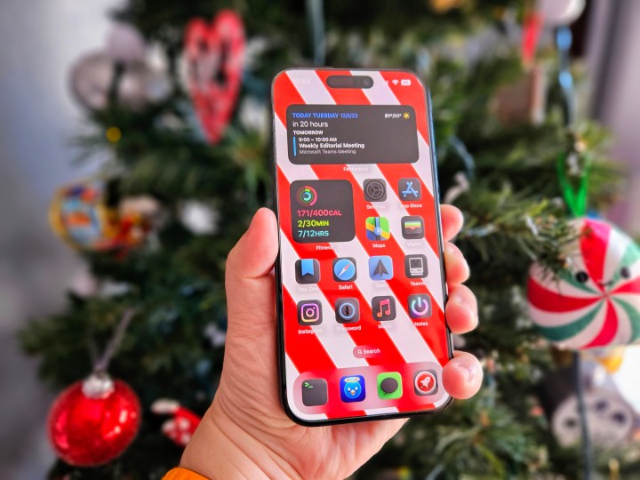 iPhone 15 Pro in der Hand vor einem Weihnachtsbaum gehalten.