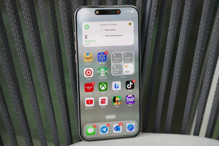 Ein iPhone 15 Pro Max sitzt aufrecht und zeigt einen seiner Startbildschirme.
