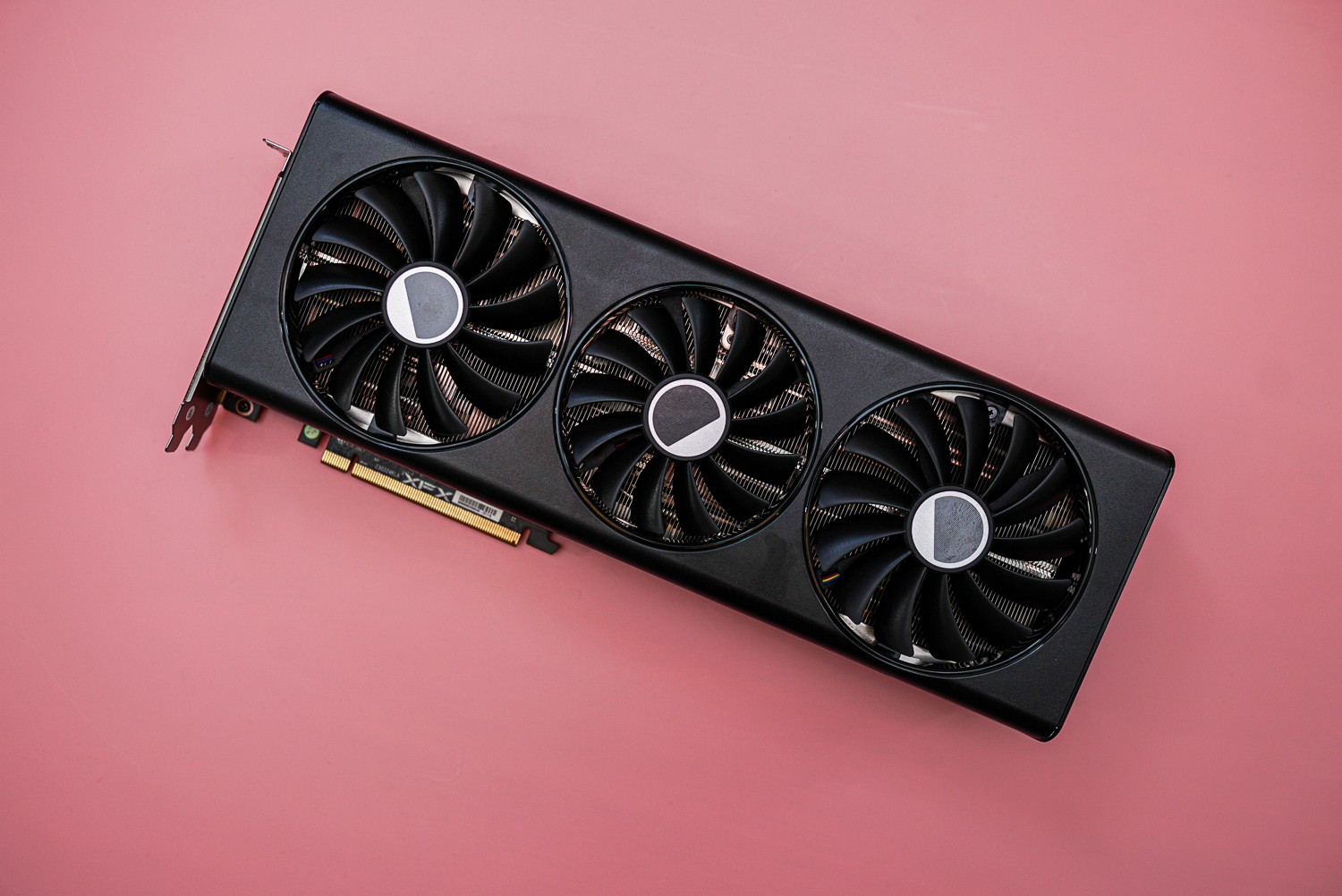 Die AMD RX 7900 Grafikkarte auf rosa Hintergrund.