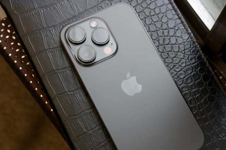 Ein schwarzes iPhone 14 Pro liegt mit der Vorderseite nach unten auf einem schwarzen Tagebuch.
