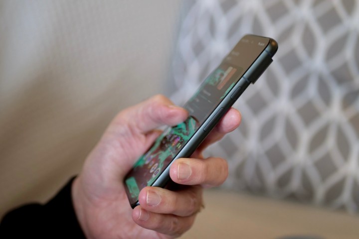 Eine Person hält das Google Pixel 8 und zeigt die Seite des Telefons.