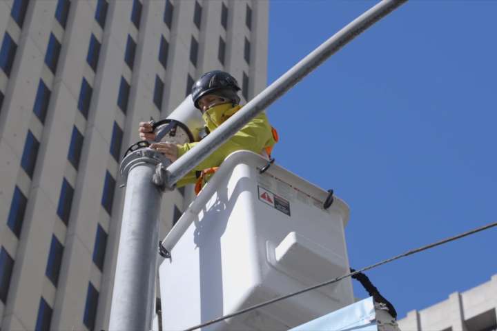 Arbeiter im Krankorb installiert 5G-Antenne an einem Gebäude.