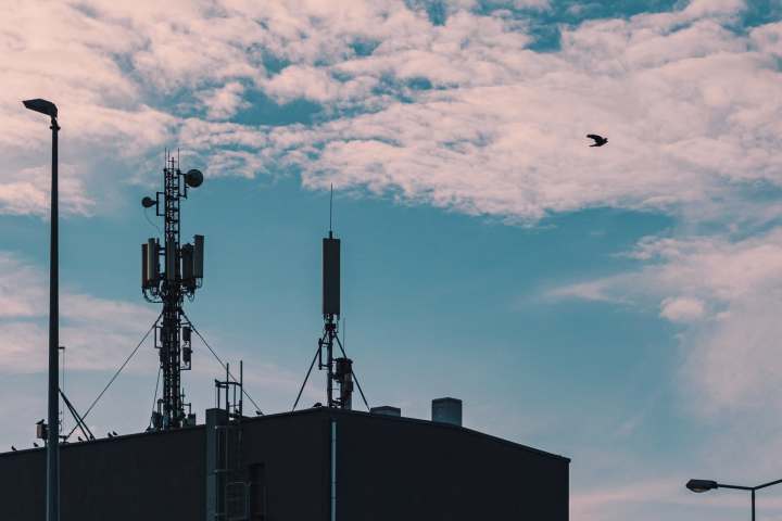 Mobilfunktürme auf dem Dach eines Gebäudes vor einem wolkenverhangenen Himmel.