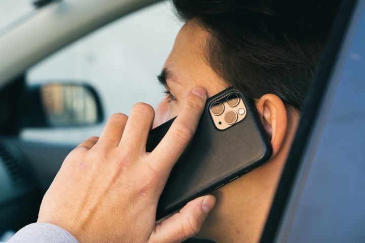 Seitenprofil einer Person in einem Auto, die ein iPhone ans Ohr hält.